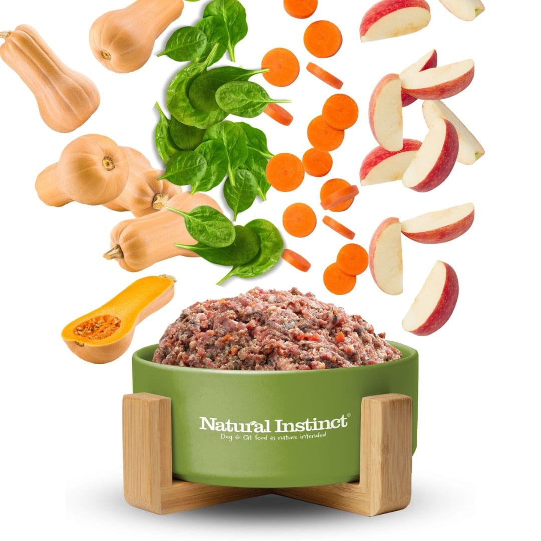 Natural Instinct bowl full with raw dog food and the ingredients falling down above